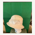 Cream cloche-style occasion hat with feather accent and delicate floral bead detail, pre-owned.